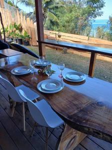 a wooden table with plates and wine glasses on a deck at Fare Ohiti, face au spot de surf de Haapiti in Haapiti +25 photos