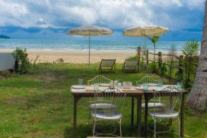 a table with chairs and umbrellas on the beach at The Shore Koh Chang Boutique Resort in Ko Chang