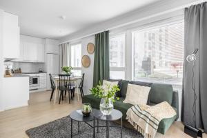 a living room with a green couch and a kitchen at Arctic Pine City Suite in Rovaniemi