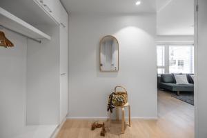 a white hallway with a mirror and a chair at Arctic Pine City Suite in Rovaniemi +7 photos