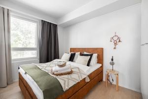 a white bedroom with a large bed with white pillows at Arctic Pine City Suite in Rovaniemi