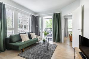 a living room with a green couch and a tv at Arctic Pine City Suite in Rovaniemi