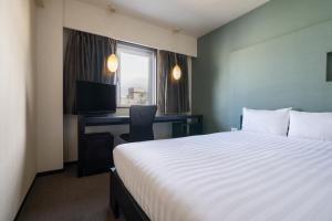 a hotel room with a bed and a desk with a computer at Hotel Vista Atsugi in Atsugi