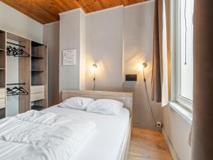 a bedroom with a bed with white sheets and a window at Ideal holiday home with garage in Blankenberge