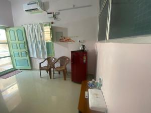 a room with two chairs and a table and a door at Vijaya Guest House in Tiruvannāmalai