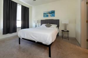 a bedroom with a large white bed and two windows at Stunning Nulu 1BR CozySuites 06 in Louisville