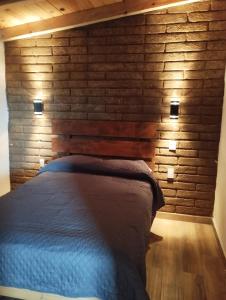 a bed in a room with a brick wall at Cabaña paraíso in Los Espinos +5 photos