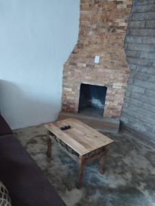 a brick fireplace with a wooden table in a room at Cabaña paraíso in Los Espinos