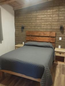 a bedroom with a bed and a brick wall at Cabaña paraíso in Los Espinos