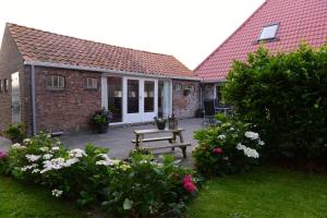 una casa con un banco y flores en el patio en Appartementen verhuur De Trijehoek, en Stiens