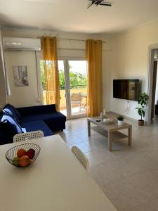 a living room with a blue couch and a table at Dimar3 Seaside Apartment in Paralia Dionysiou