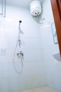 una ducha en un baño de azulejos blancos en JRéside Appart Bleu 50m2 centre-ville, en Cotonou