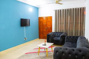 Una sala de estar con dos sofás negros y un televisor. en JRéside Appart Bleu 50m2 centre-ville, en Cotonou