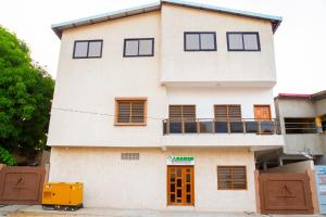 un edificio blanco con puertas y ventanas de color naranja en JRéside Appart Bleu 50m2 centre-ville, en Cotonou