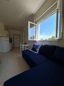 a living room with a blue couch and a large window at Dimar3 Seaside Apartment in Paralia Dionysiou