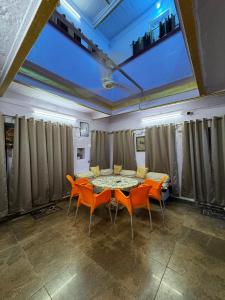 a dining room with a table and orange chairs at The Golden Lodge Varanasi in Varanasi