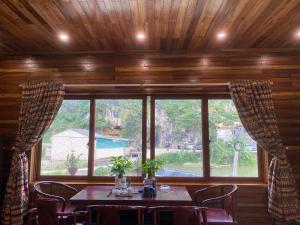 a dining room with a table and a large window at Lan Rừng Homestay in Lũng Niêo