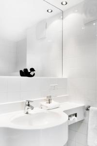 a white bathroom with a sink and a mirror at Augarten Art Hotel in Graz