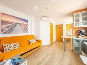 Una sala de estar con un sofá naranja en una cocina. en Ático de Lujo Plaza Ayuntamiento, en Valencia