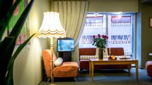 a living room with a lamp and a chair and a table at ARIBĖ Hotel Klaipėda, Free Parking in Klaipėda