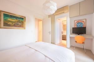 a white bedroom with a white bed and a orange chair at Mourtia LA0414 in AthÃ©aton