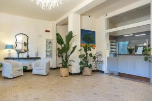 a lobby with white chairs and a reception desk at Hotel Massimo in Marina di Cecina