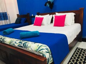 two beds in a room with blue and red pillows at Yala Grand Homestay in Tissamaharama