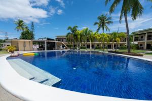 a large pool with blue water and palm trees at Malinawon Resort 馬莉吶灣度假中心 in Panglao Island