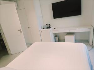 a bedroom with a white bed and a flat screen tv at Ibiscus Hotel in Rhodes Town