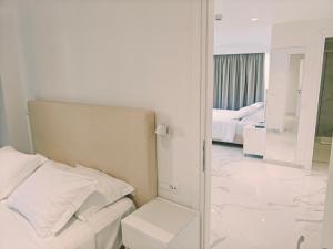a white bedroom with a bed and a mirror at Ibiscus Hotel in Rhodes Town