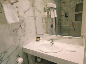 a white bathroom with a sink and a mirror at Ibiscus Hotel in Rhodes Town