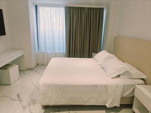a bedroom with a white bed and a window at Ibiscus Hotel in Rhodes Town