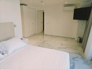 a bedroom with a white bed and a tiled floor at Ibiscus Hotel in Rhodes Town