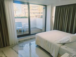 a bedroom with a bed and a balcony with a table at Ibiscus Hotel in Rhodes Town