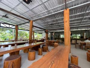 a restaurant with wooden benches and tables and chairs at The Camper Lodge Khao Sok in Ban Bang Bon