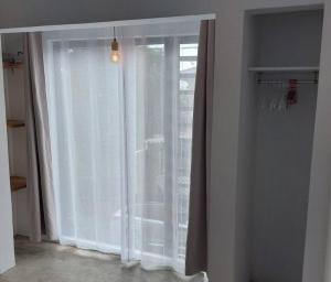 a window with white curtains in a room at Maison familiale in Curepipe