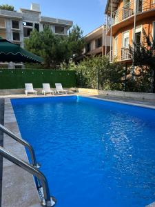 a swimming pool with two white chairs next to a building at Paradise Shekvetili in Shekhvetili