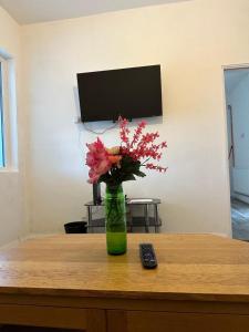 Un jarrón con flores sobre una mesa junto a un mando a distancia. en Shakespeare House 6 bedroom 10 beds stay up to 14 people, en Derby