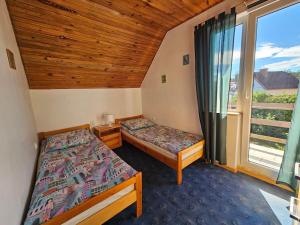 two beds in a room with a large window at Dom Letniskowy nad jeziorem in Wilkasy