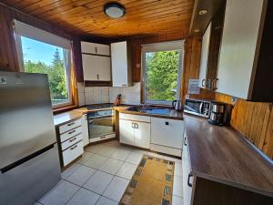 a kitchen with white cabinets and a wooden ceiling at Dom Letniskowy nad jeziorem in Wilkasy