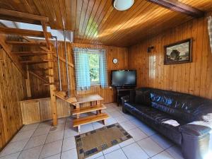a living room with a black leather couch and a tv at Dom Letniskowy nad jeziorem in Wilkasy