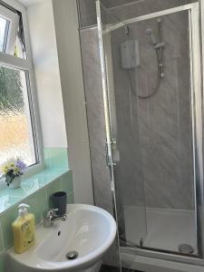 Un baño con lavabo y ducha con puerta de cristal. en Shakespeare House 5 bedroom 7 beds stay up to 12 people, en Derby