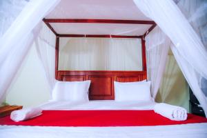 a bed with a red blanket and white pillows at Freedom Guest Inn Ella in Ella
