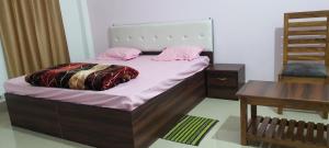 a bedroom with a bed with pink pillows and a table at Chitrakoot palace in Ayodhya