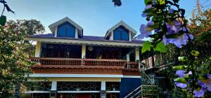 a blue house with a balcony and purple flowers at Dean Dale Cottages in Thekkady