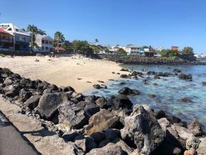 a beach with rocks and people in the water at Case Terre Sainte - Maison meublée F3 in Saint-Pierre