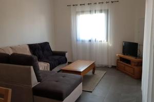 a living room with a couch and a tv at Case Terre Sainte - Maison meublée F3 in Saint-Pierre