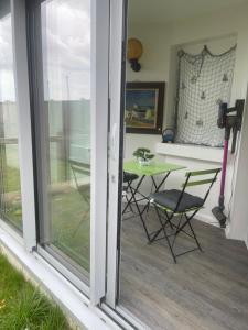 a sliding glass door with a table and chairs on a patio at Apparemment front de mer in Ouistreham +6 photos