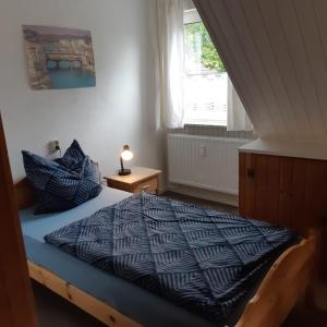 a bedroom with a bed with a blue comforter and a window at Nordseeferienhaus Peter in Niebüll