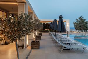 a row of chairs and umbrellas next to a pool at Asteris Hotel in Skala